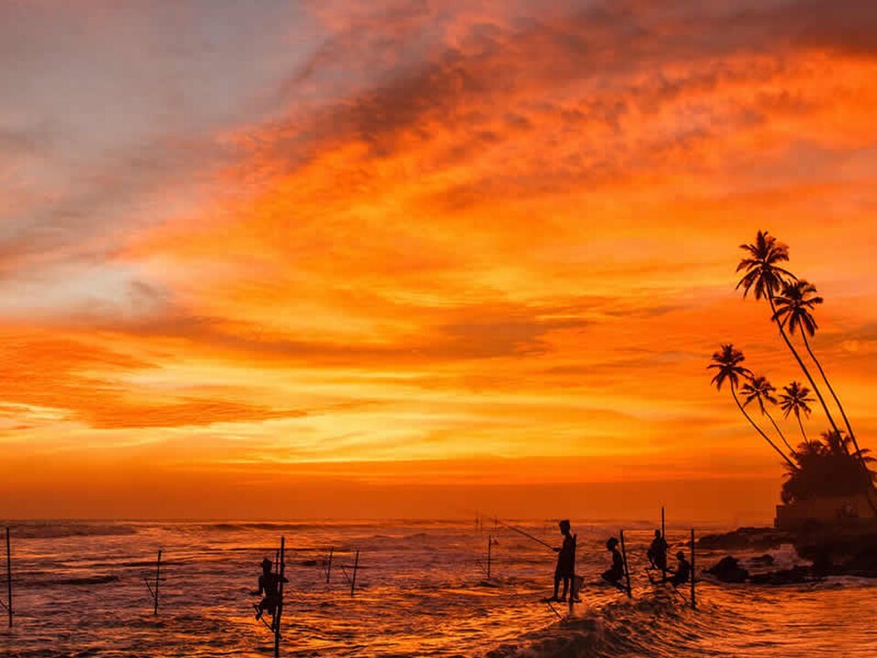 Golden sunrise over Sri Lanka's coastline with silhouetted fishing boats